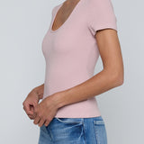 Person wearing a pink top and blue jeans on a plain background