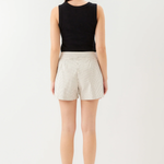 Person wearing a black sleeveless top and white striped shorts on a white background
