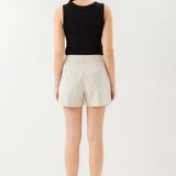 Person wearing a black sleeveless top and white striped shorts on a white background