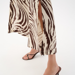 Person wearing zebra print pants and black sandals on a white background