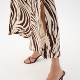 Person wearing zebra print pants and black sandals on a white background