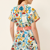 Woman wearing a colorful floral dress with a belt on a beige background
