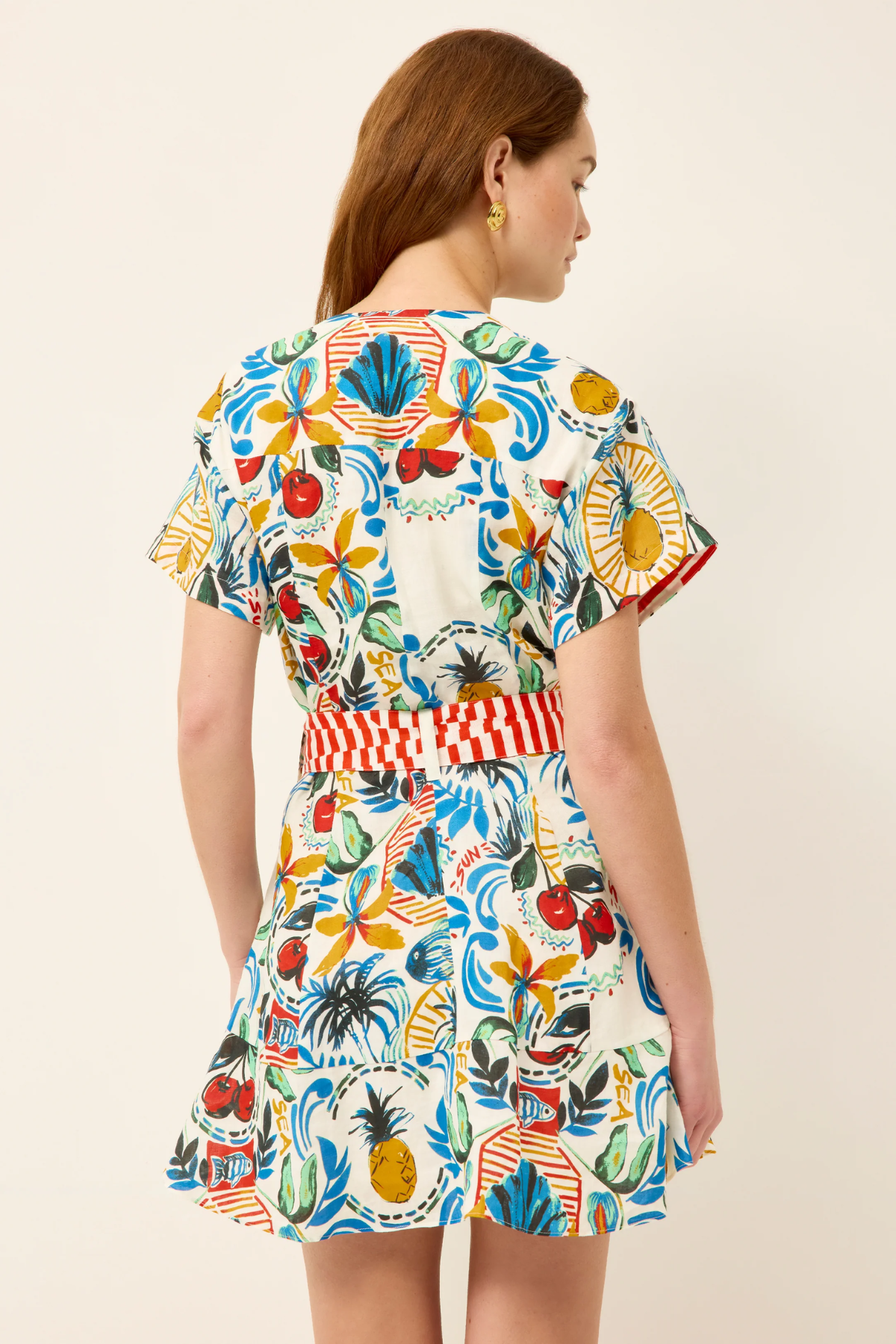 Woman wearing a colorful floral dress with a belt on a beige background