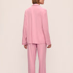 Person wearing a pink pajama set against a beige background