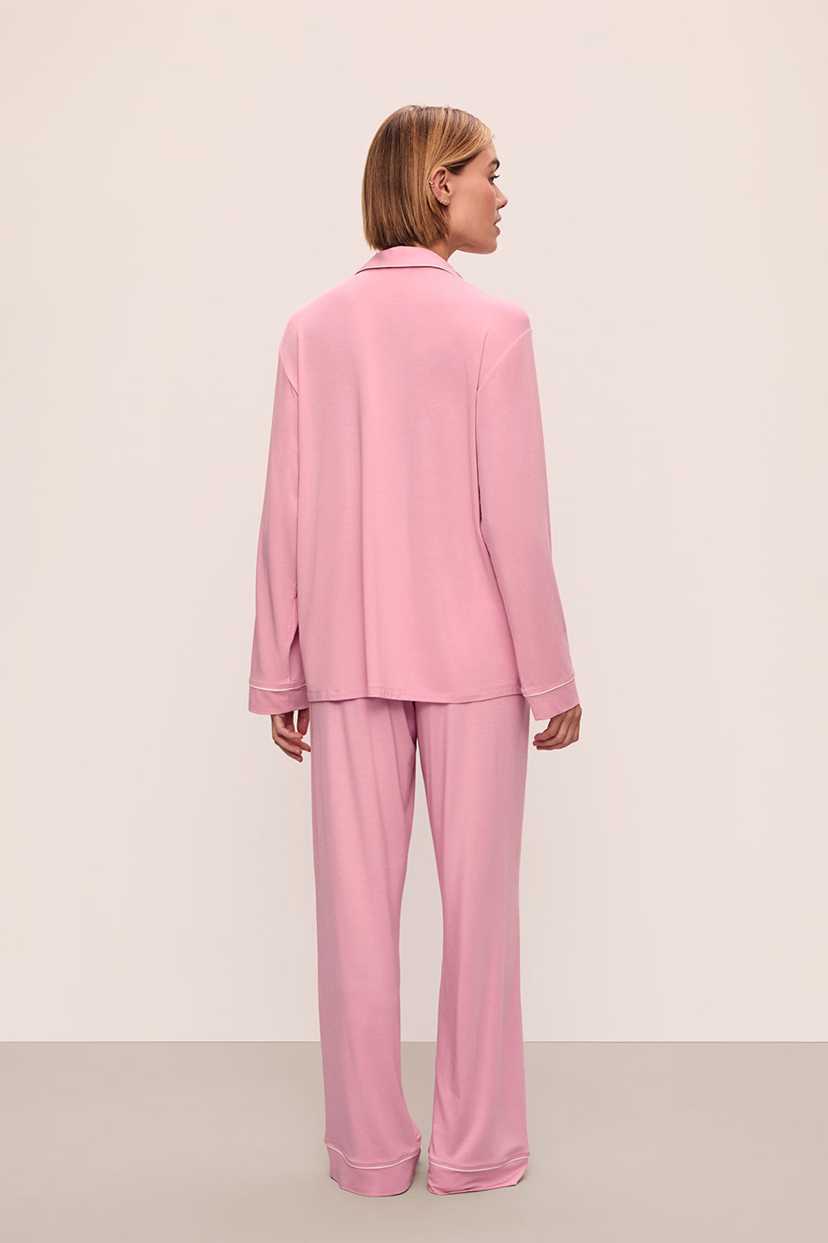 Person wearing a pink pajama set against a beige background