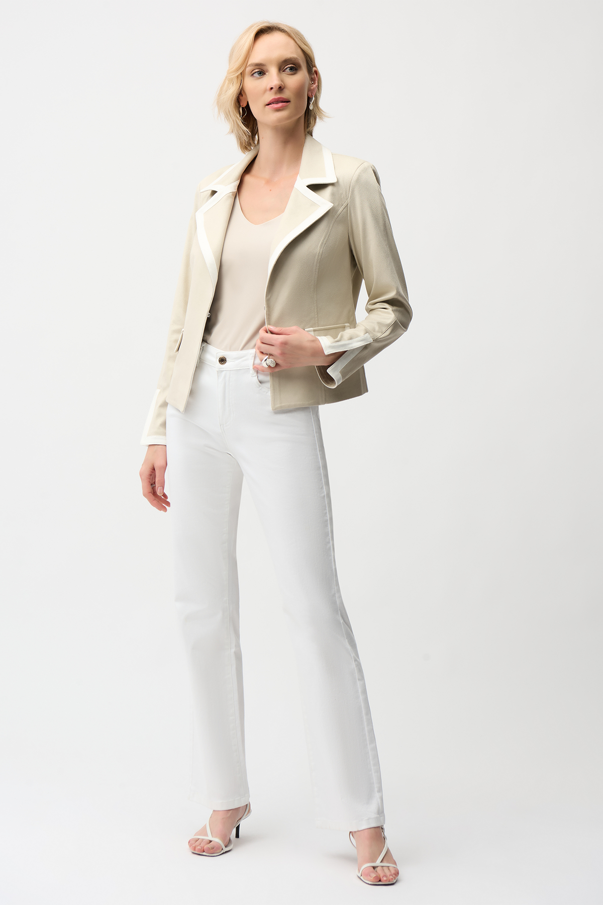 Woman wearing a beige blazer and white pants on a white background