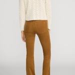 Rear view of a model wearing a cream cable-knit cropped sweater and brown corduroy flare pants against a light gray studio background.