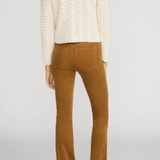 Rear view of a model wearing a cream cable-knit cropped sweater and brown corduroy flare pants against a light gray studio background.