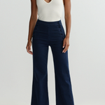 Person wearing a white halter top and navy wide-leg pants on a light gray background