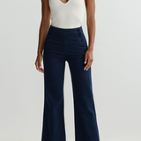 Person wearing a white halter top and navy wide-leg pants on a light gray background