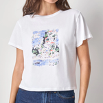 Woman wearing a white t-shirt with a colorful graphic design on a plain background