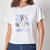 Woman wearing a white t-shirt with a colorful graphic design on a plain background