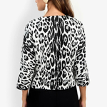 A woman shown from the back wearing a black and white leopard print top with three-quarter sleeves and black pants, against a plain white background.