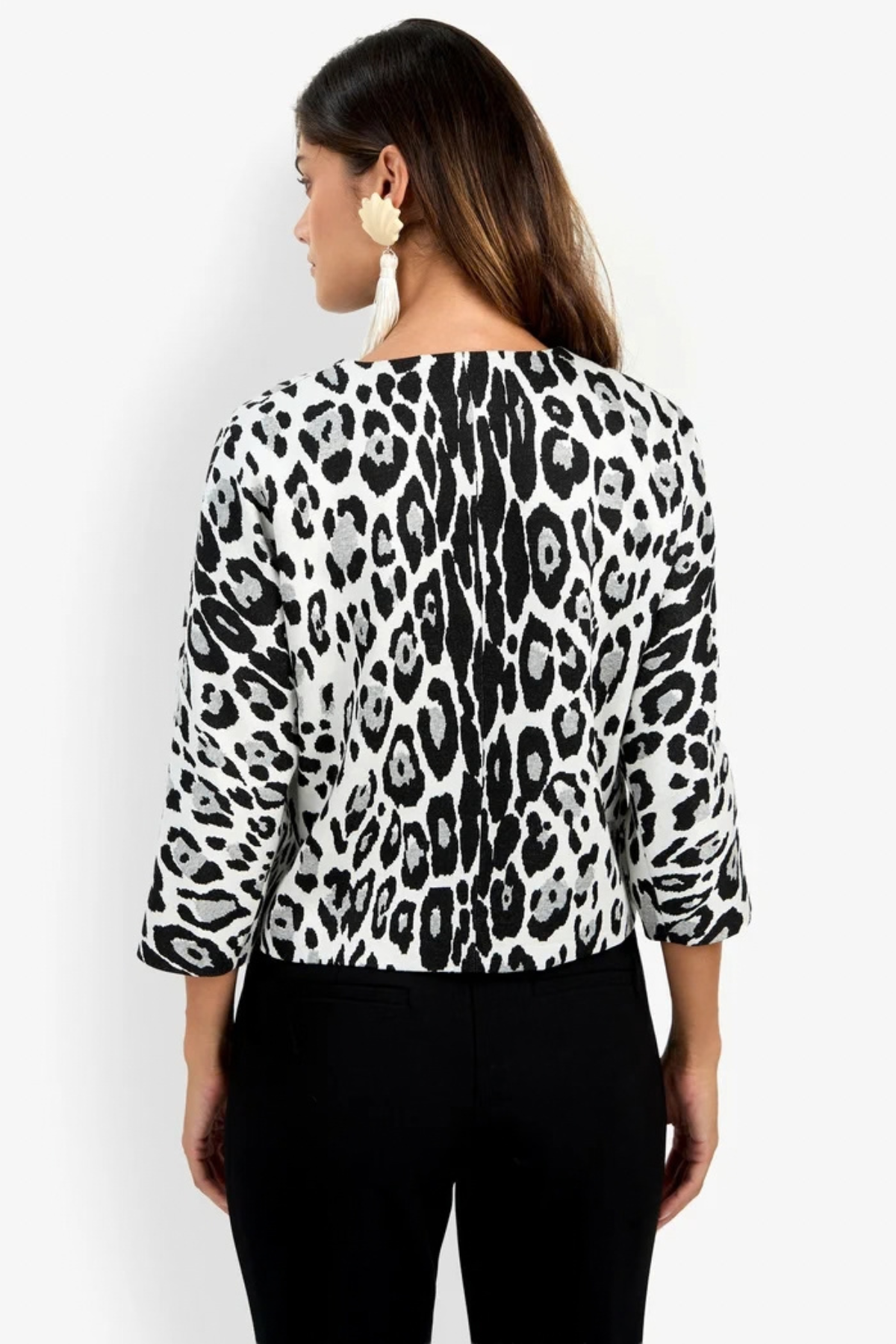 A woman shown from the back wearing a black and white leopard print top with three-quarter sleeves and black pants, against a plain white background.