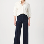 Woman wearing a white blouse and dark blue pants on a white background