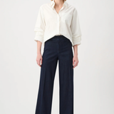 Woman wearing a white blouse and dark blue pants on a white background