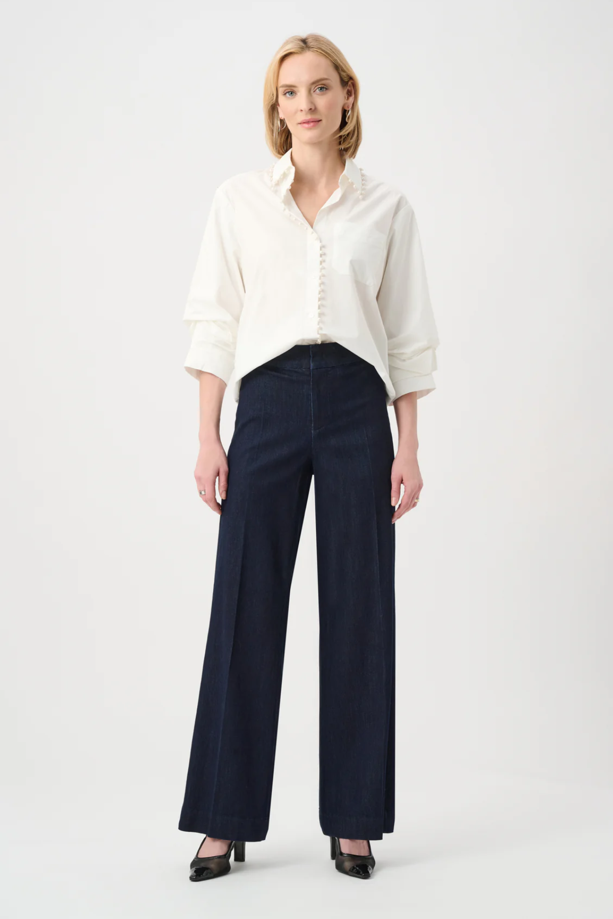 Woman wearing a white blouse and dark blue pants on a white background