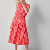 Woman wearing a red dress with a white floral pattern on a gray background