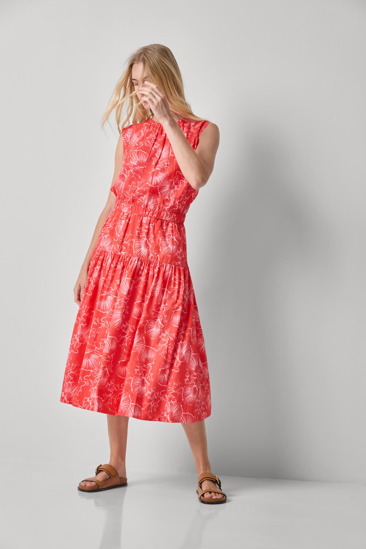 Woman wearing a red dress with a white floral pattern on a gray background