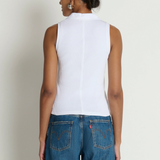 Person wearing a white sleeveless top and blue jeans against a plain background
