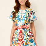 Woman wearing a colorful floral dress with a belt on a beige background