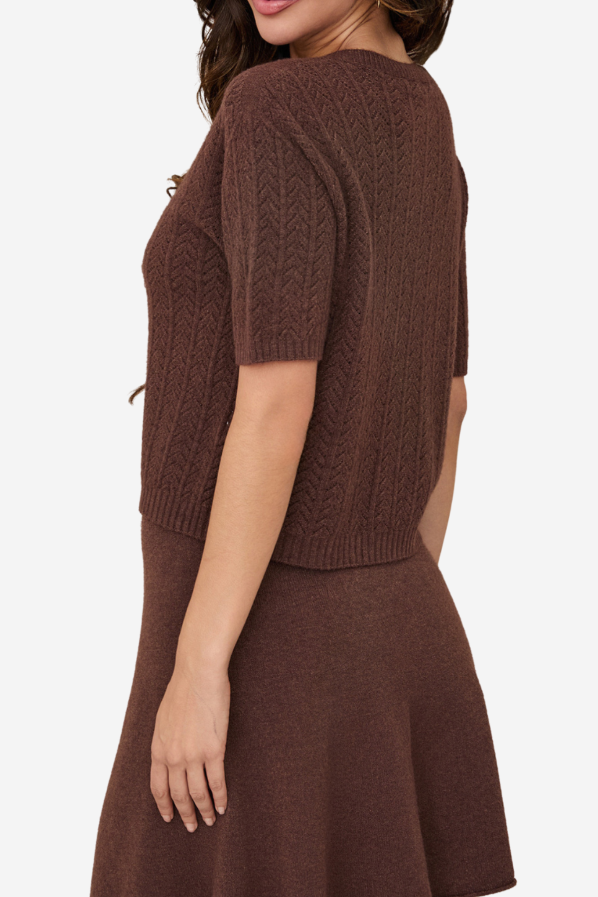 A woman shown from the back wearing a brown short-sleeve knit sweater and matching brown skirt against a plain light background.