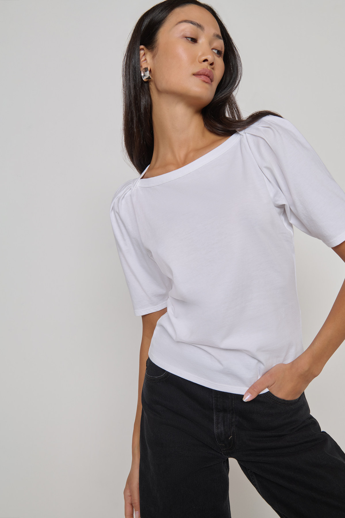 Woman wearing a white top and black pants against a plain background