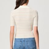 Model wearing a white printed blouse with colorful accents and short sleeves.