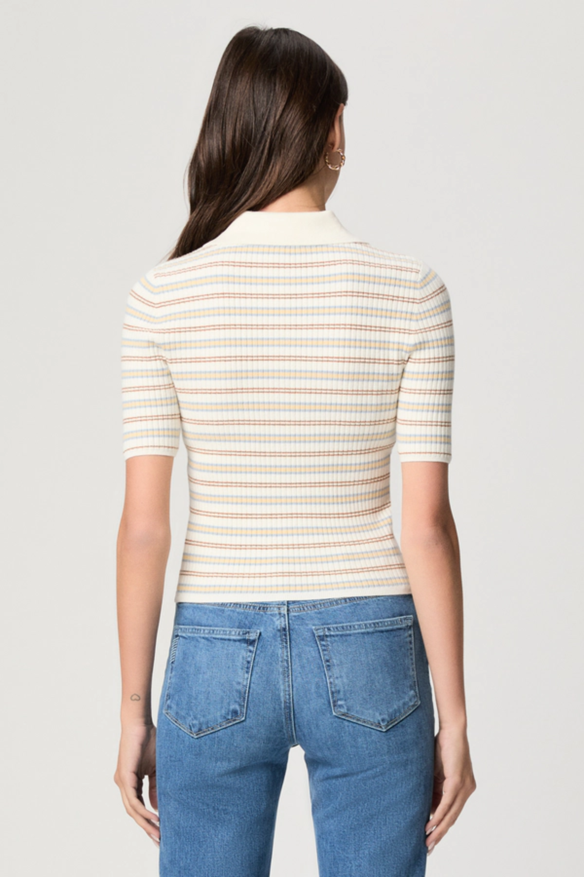 Model wearing a white printed blouse with colorful accents and short sleeves.