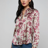 Woman wearing a floral blouse and jeans on a gray background