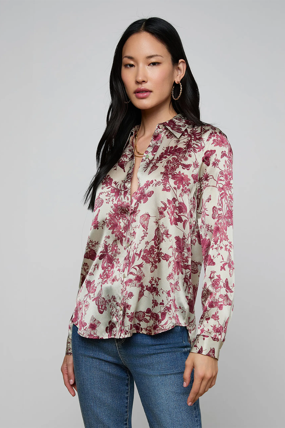Woman wearing a floral blouse and jeans on a gray background