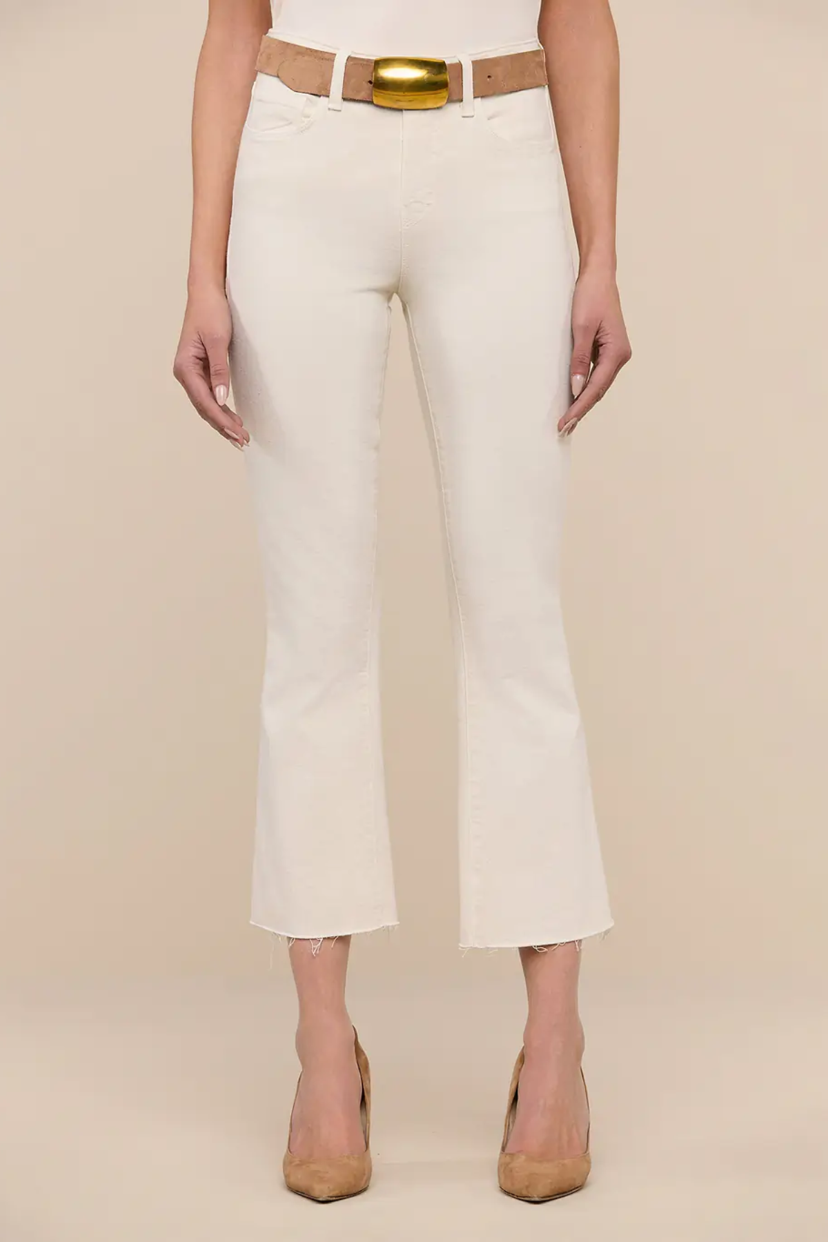 Person wearing white pants with a gold belt on a beige background