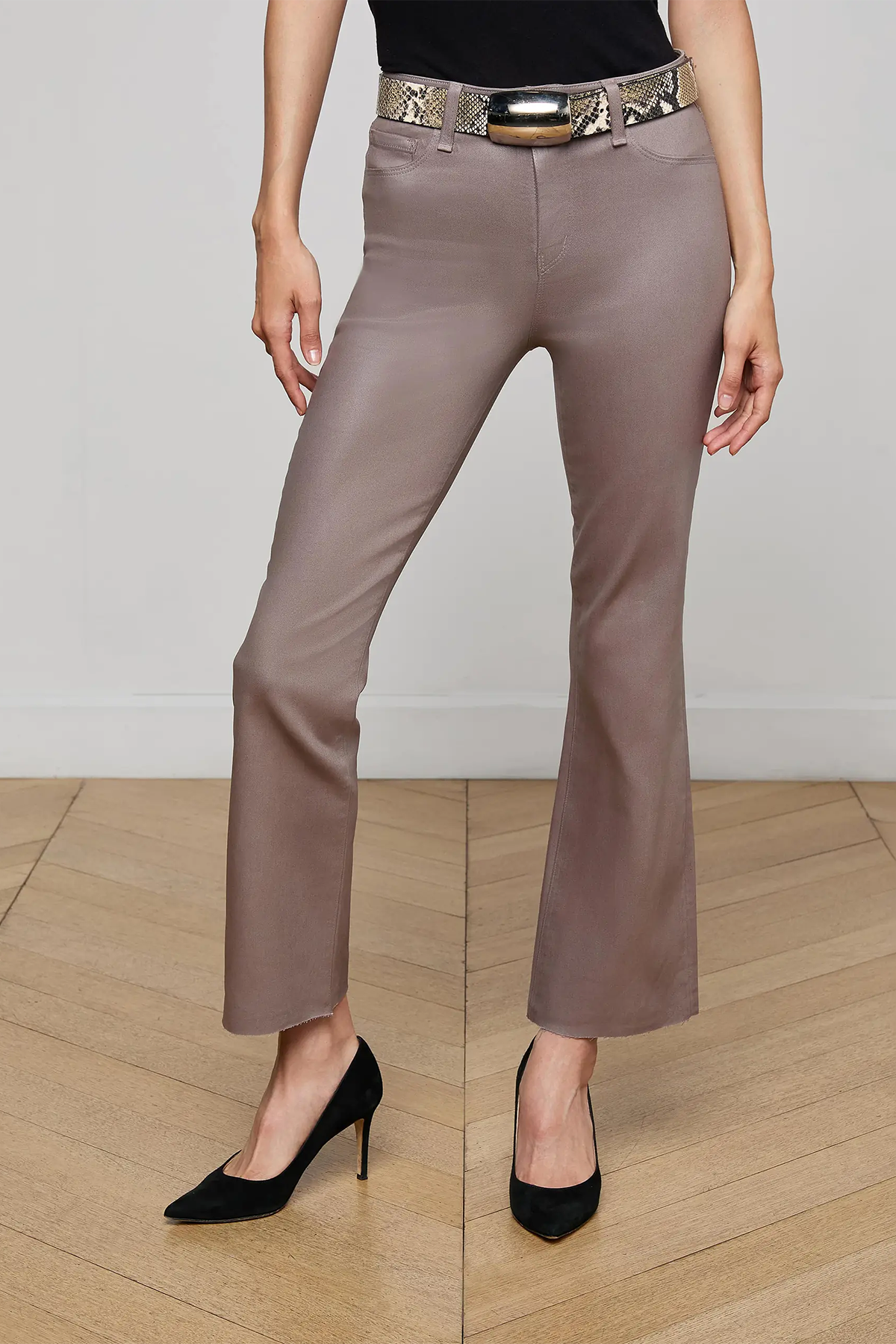 Person wearing brown pants with a decorative belt on a wooden floor.