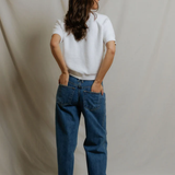 back of woman in white top and denim on draped background 