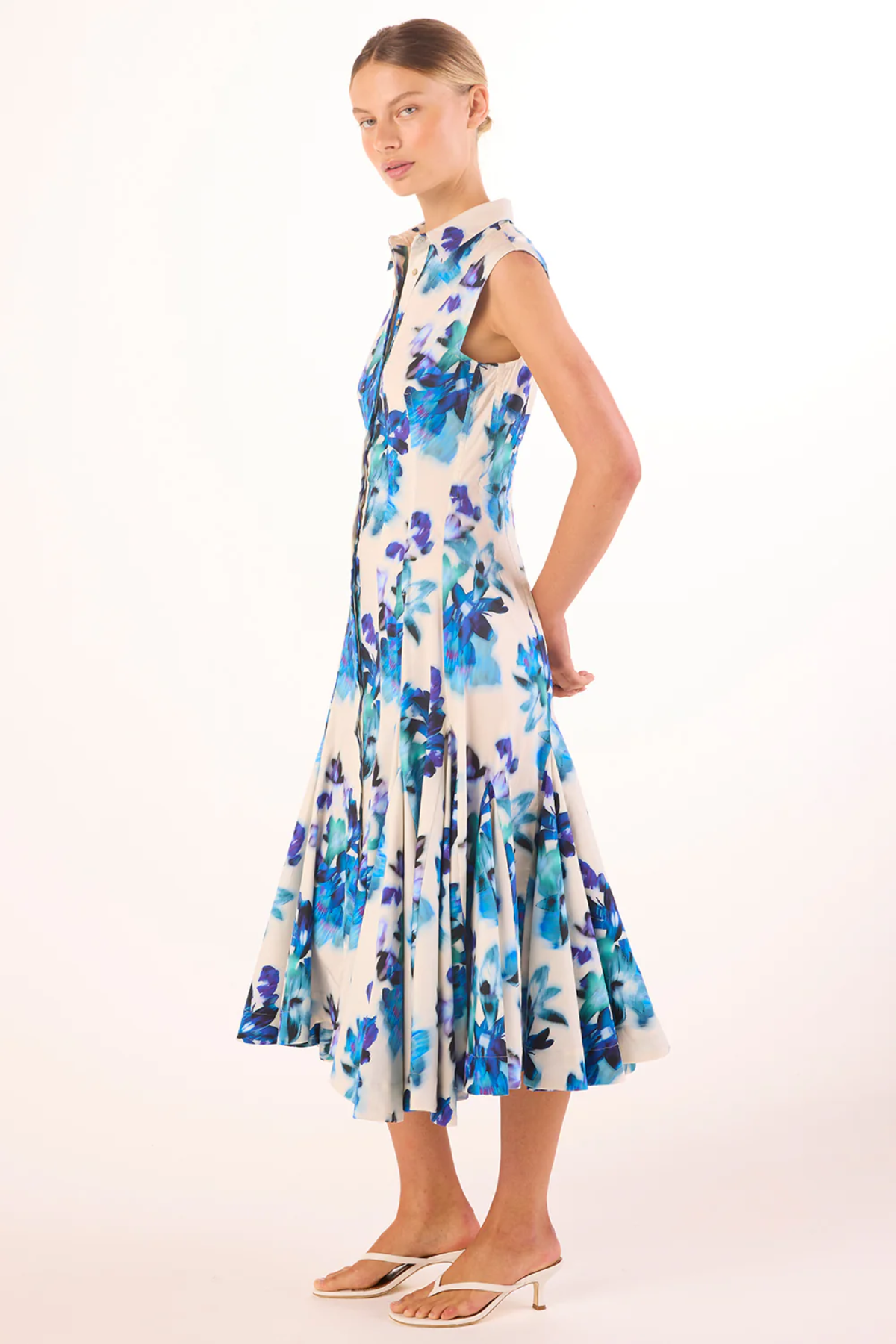 Woman wearing a floral dress with blue and purple flowers on a white background