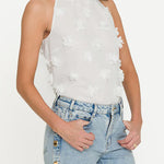Woman wearing a white floral halter top and blue jeans on a white background