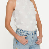 Woman wearing a white floral halter top and blue jeans on a white background