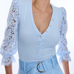 woman in light blue ribbed and lace top on white background 