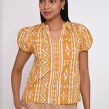 Model wearing a sleeveless orange printed blouse with a relaxed silhouette.