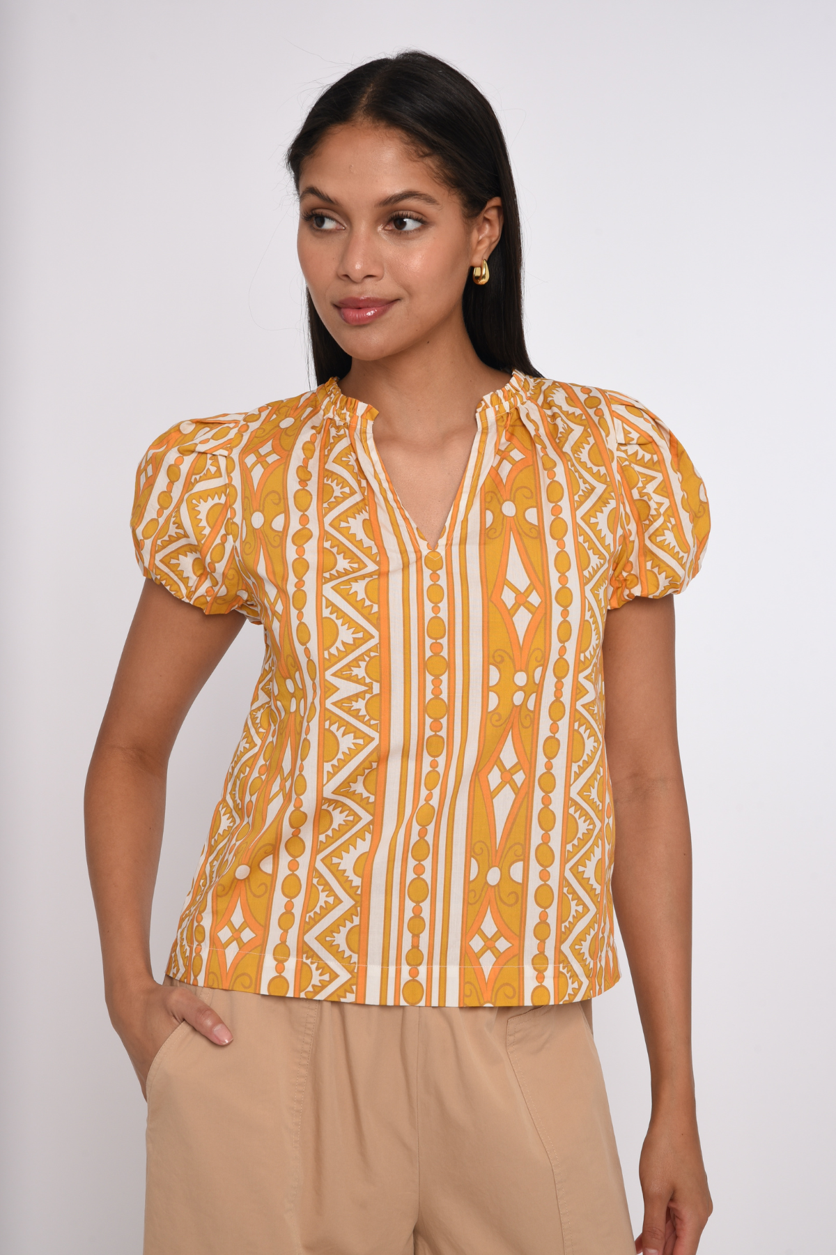 Model wearing a sleeveless orange printed blouse with a relaxed silhouette.