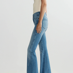 Person wearing blue flared jeans on a white background