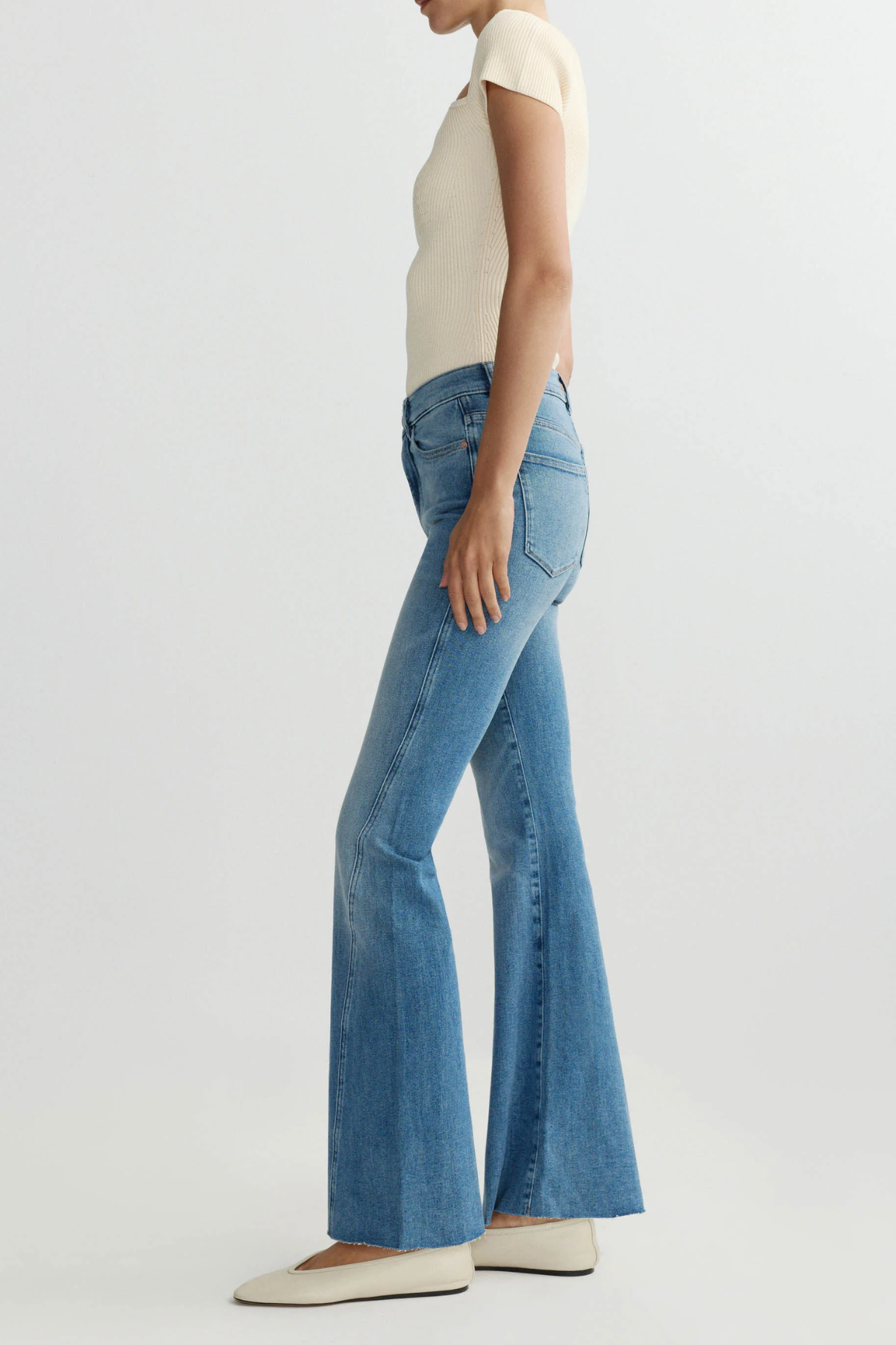 Person wearing blue flared jeans on a white background
