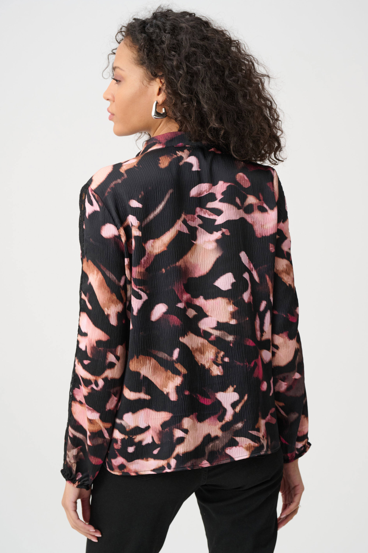 Woman wearing a patterned blouse with a neutral background