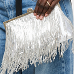 Silver fringe clutch held by a person wearing blue jeans