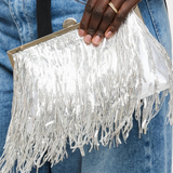 Silver fringe clutch held by a person wearing blue jeans