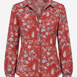 A red long-sleeve western-style button-up shirt with a paisley and floral print, featuring contrast stitching along the collar and shoulders, shown against a plain light gray background.
