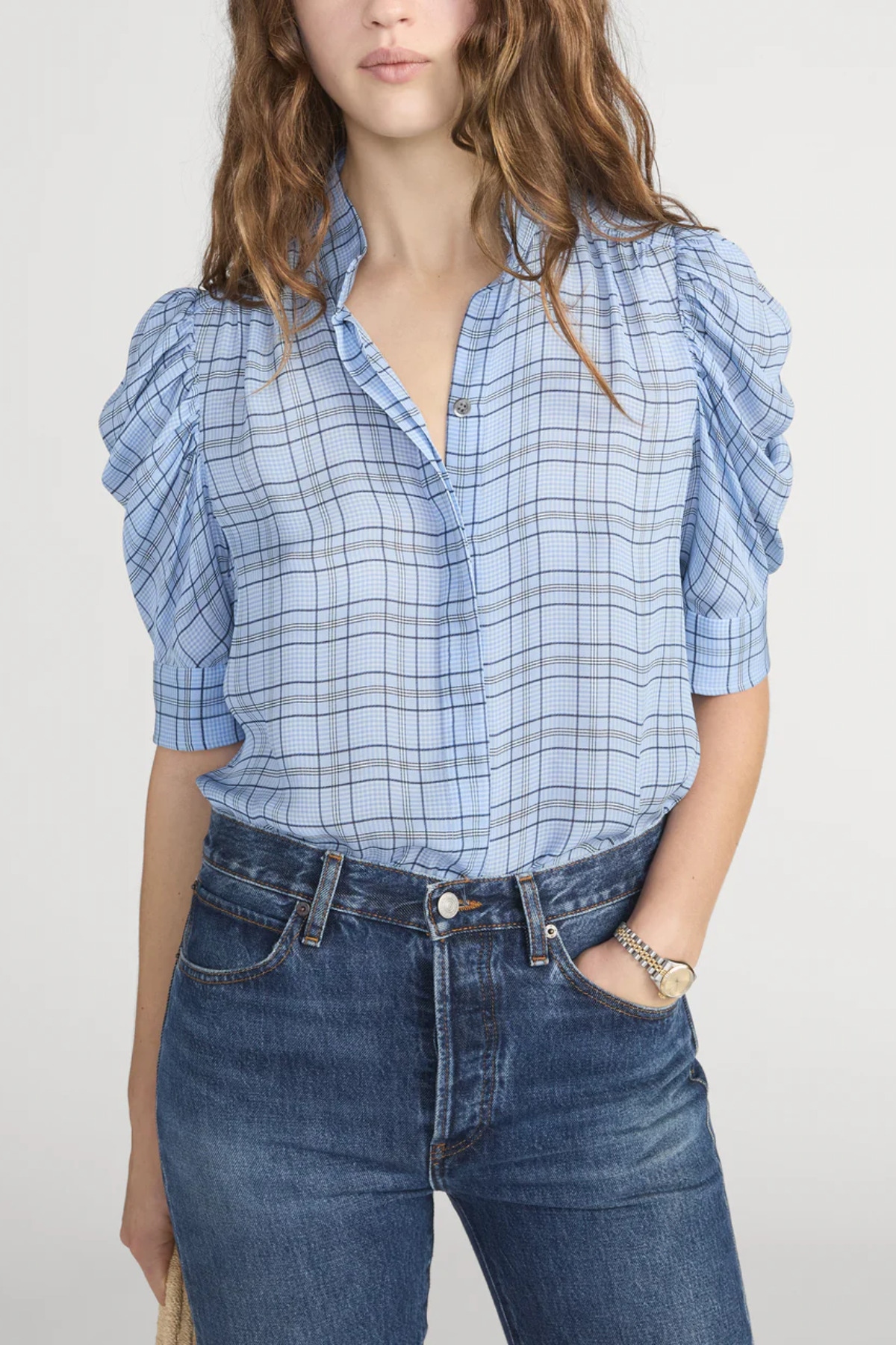 Person wearing a blue plaid shirt and jeans on a plain background
