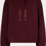 A dark burgundy cropped hoodie with matching drawstrings, displayed against a light gray background.