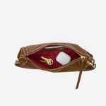 A brown leather zippered pouch shown open against a light gray background, revealing a deep burgundy interior with a gold key and a white wireless earbud case inside.