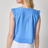 Woman wearing a blue sleeveless top with ruffled shoulders on a plain background